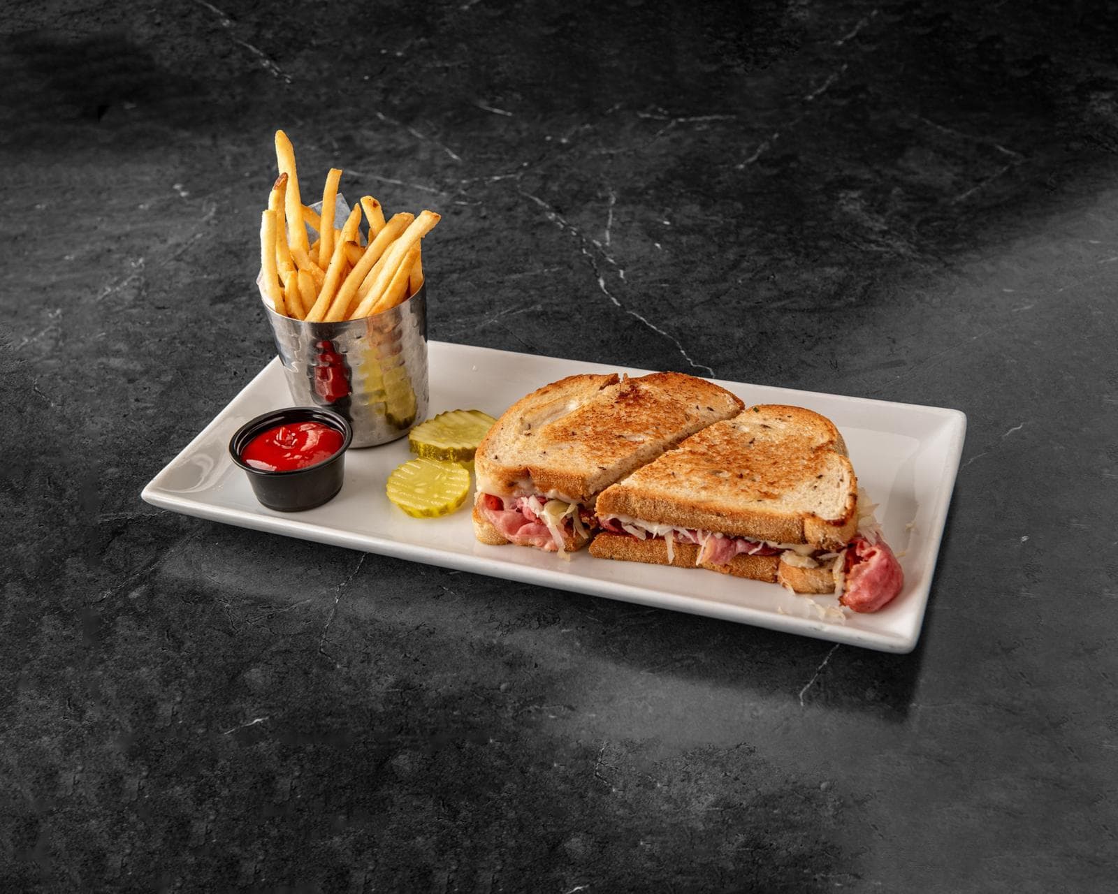 Corned Beef Reuben on grilled rye with fries and pickles