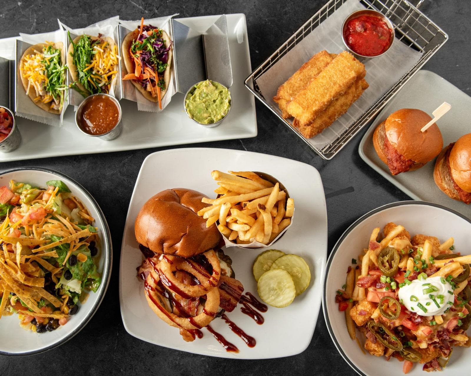 A spread of HOME favourites — tacos, sliders, burger, salad and loaded frots