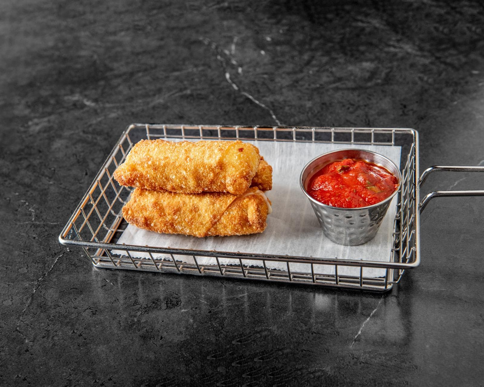 Jumbo mozzarella sticks in a fry basket with marinara