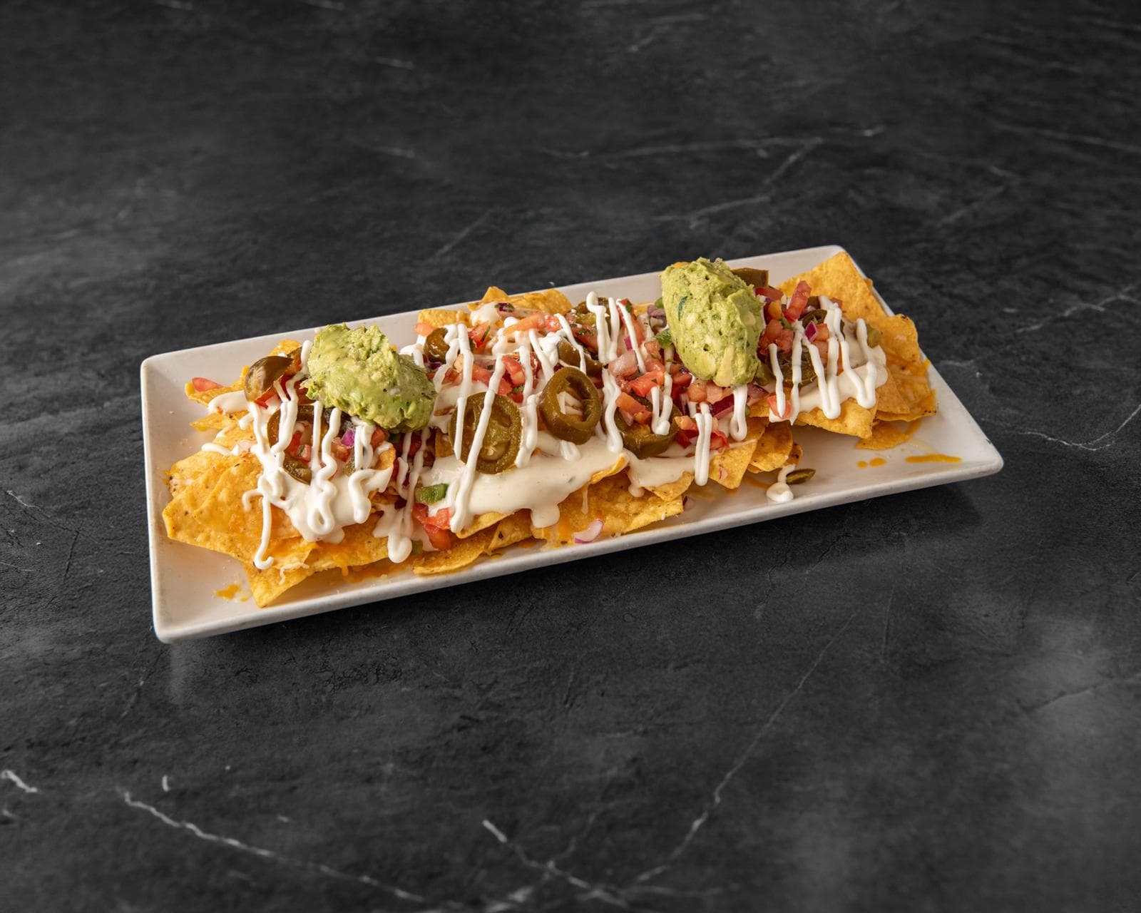 Nachos layered with cheese, jalapeños, pico de gallo and guacamole