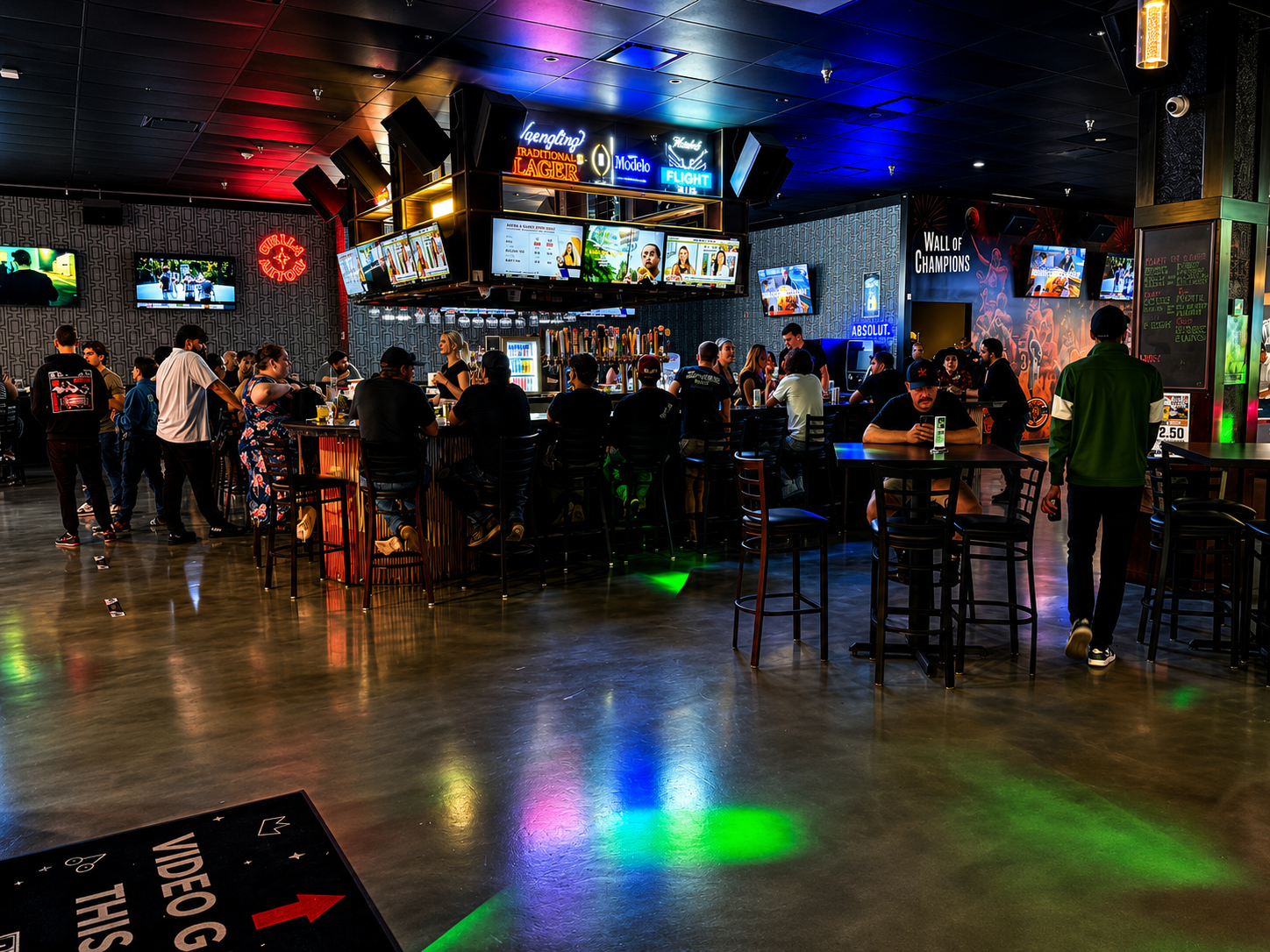 Guests gathered at the bar counter under neon lighting inside HOME Sports Bar