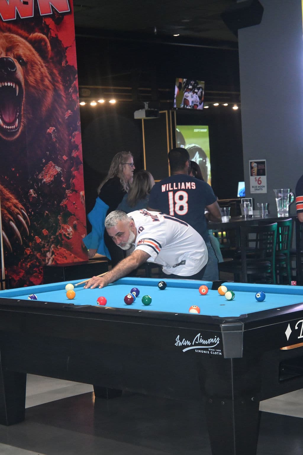 A fan in a Bears jersey lining up a shot at the pool table